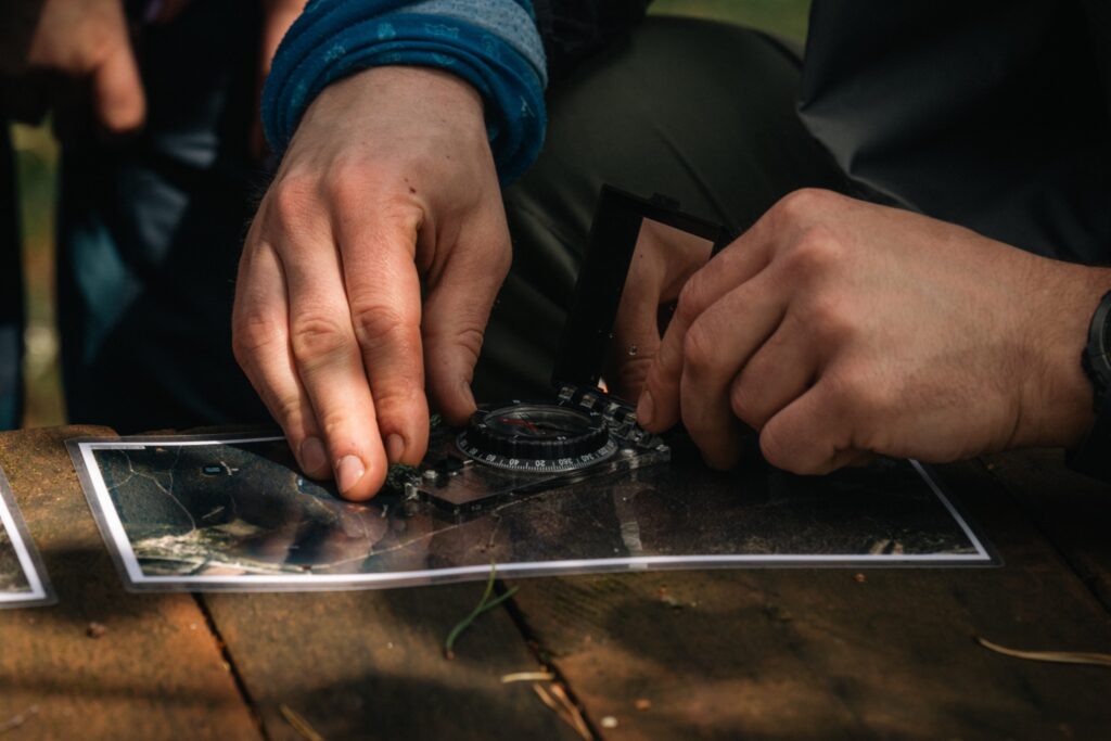 Rankos nustato kompaso kryptį ant žemėlapio per Edge of Survive orientavimosi mokymus