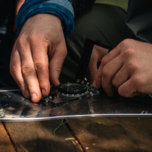 Rankos nustato kompaso kryptį ant žemėlapio per Edge of Survive orientavimosi mokymus